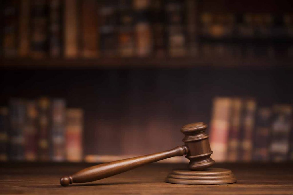 Legal theme with court gavel and bookshelves in background.
