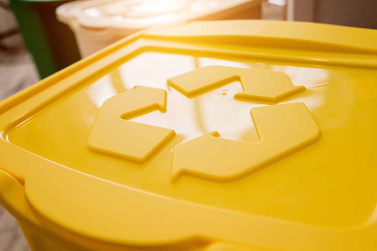 Yellow recycle container with chasing arrows symbol.